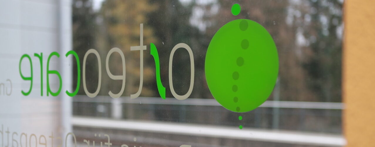 Schriftzug Osteocare auf der Fensterscheibe der Praxis.