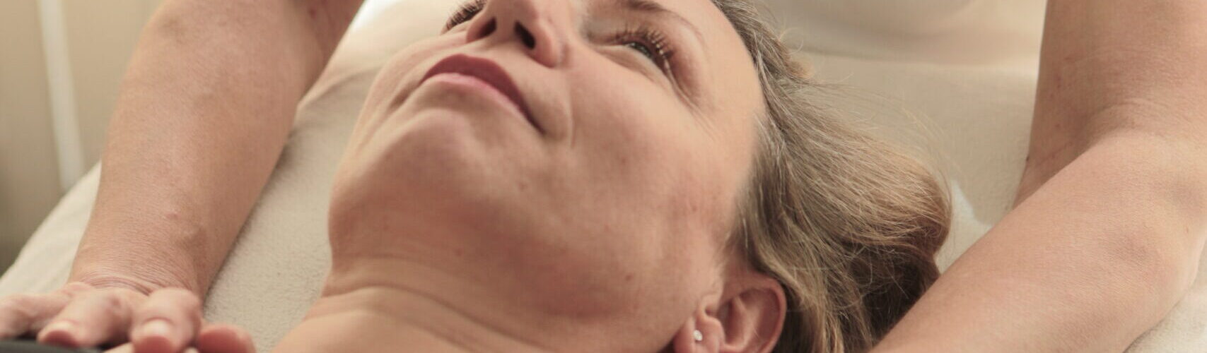 Liegende Frau in Osteopathie-Behandlung. Text im Bild: Natürlich wieder gut. Ganzheitliche Behandlung durch Osteopathie.